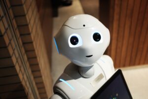 Robotica in de zorg: vervangers óf ondersteuners van de zorgverlener? De toekomst van robots in de zorg lijkt dichterbij dan ooit. Ze duiken overal op: in ziekenhuizen, verpleeg- en verzorgingshuizen, in de psychiatrische zorg én in de thuiszorg. Zorgrobots worden in een rap tempo in allerlei soorten en maten op de markt gebracht en nemen steeds meer menselijke handelingen over. Benieuwd wat je kunt verwachten van robotica in de zorg en hoe het toekomstbeeld eruitziet? Lees dan snel verder. Zo wordt robotica in de zorg ingezet Vandaag de dag hebben robots in de zorg voornamelijk een ondersteunende functie. De meeste zorgrobots zijn gemaakt voor één specifieke activiteit. Een zelfstandige zorgrobot die overal ingezet kan worden, bestaat (nog) niet. Robots zijn uitermate geschikt om repetitieve of fysiek zware werkzaamheden over te nemen waar zorgpersoneel veel tijd aan kwijt is. Zo kunnen ze medicatie, beddengoed of wasgoed over verschillende verdiepingen verplaatsen, bezoekers ontvangen, de weg wijzen en ruimtes desinfecteren. In de thuis- en ouderenzorg kunnen zorgrobots mensen die moeilijk ter been zijn ondersteuning bieden bij alledaagse activiteiten door bijvoorbeeld producten aan te geven, eten te serveren en te helpen met schoonmaken. Ook kunnen ze vergeetachtige ouderen herinneren aan hun medicatie en dementerende ouderen vragen stellen om hun geheugen te trainen. De mogelijkheden van robotica in de zorg De mogelijkheden van robotica in de zorg zijn afhankelijk van het niveau van de kunstmatige intelligentie die is toegepast. Dat kan zijn op analytisch, intuïtief of empathisch niveau. Analytische intelligentie is gebaseerd op systematisch leren uit big data en maakt logisch denken mogelijk bij besluitvorming. Vandaag de dag is dat al ver ontwikkeld, waardoor robots zich perfect lenen voor taken als vragen beantwoorden van mensen en zelfstandig bewegen en helpen op een afdeling. Wat op dit moment nog niet goed genoeg ontwikkeld is, is intuïtieve en empathische intelligentie. Deze zorgen ervoor dat robots emoties herkennen, contextueel denken en passend en natuurlijk reageren. Technologie ontwikkelt zich echter snel, waardoor deze functies en mogelijkheden hoogstwaarschijnlijk snel in de toekomst worden uitgebreid. Vervangen robots zorgverleners in de toekomst? Hoe ziet het toekomstbeeld er dan uit: gaan robots alle zorgverleners vervangen? Waarschijnlijk niet. De toekomst van de zorg zal naar verwachting een blended of hybride vorm zijn: een combinatie van menselijke en technologische zorg. Robots doen dan het mechanische en analytische werk zodat de zorgverlener meer tijd heeft om kwalitatieve, persoonlijke zorg te kunnen verlenen. Robots gaan waarschijnlijk taken verrichten als deuren openen, opruimen, afstoffen, koffie of thee zetten, ondersteunen bij operaties en de administratie doen. Menselijke hulp blijft echter altijd nodig. Dat heeft te maken met wensen en verlangens van mensen die niet eenvormig en voorspelbaar zijn (aan de kant van de zorgvraag) en met de unieke vermogens van mensen, zoals empathie, creativiteit en oplossingsgerichtheid (aan de kant van de zorgverlener). Daarnaast moeten robots worden geprogrammeerd en bediend. Robotica in de zorg zal in de toekomst dus een fijne samenwerking zijn om de werkdruk te verlichten, zodat zorgverleners zich meer kunnen richten op echte menselijke zorg, sociaal contact en persoonlijke aandacht. Maar wie weet wat de verre toekomst biedt?
